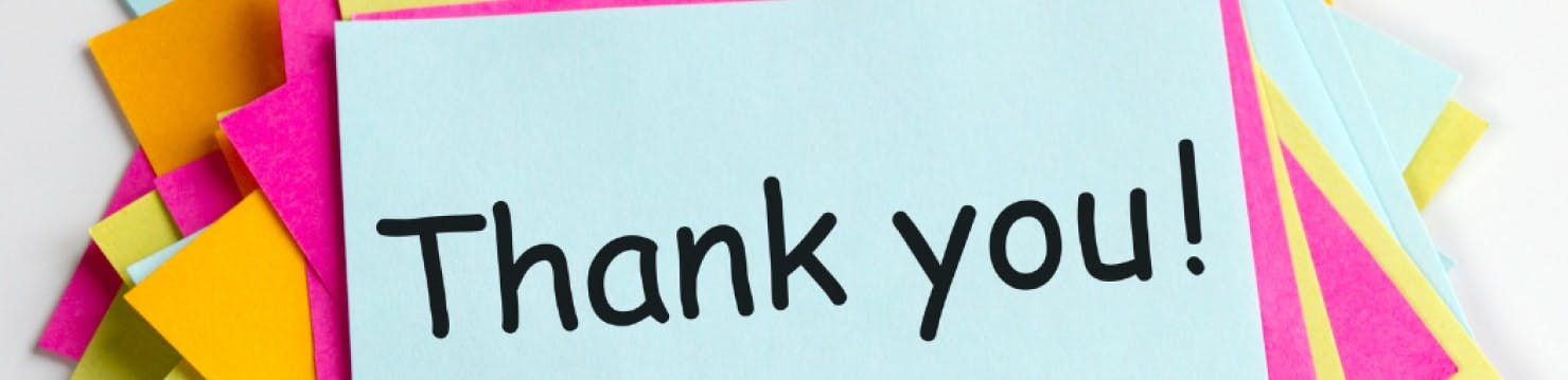 A note that says thank you stacked on top of pink and yellow post-it notes.